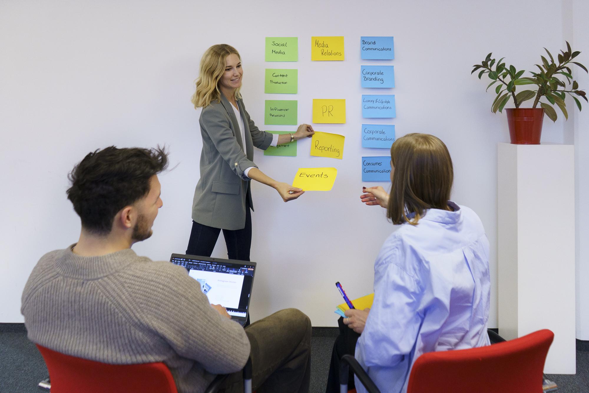 Three people working with Post-Its as part of a brainstorming session.